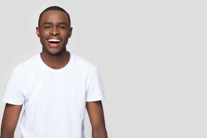 man in a white shirt smiling wide with a perfect white smile on a white background cosmetic dentistry dentists in Annapolis Maryland